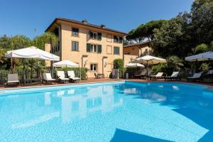 a swimming pool with chairs and umbrellas in front of a building at Hotel Cavalieri Del Mare in Marina di Massa