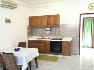 a kitchen with wooden cabinets and a white table and a table and chairs at House Dina in Pula