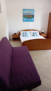 a bedroom with two beds with purple sheets on them at Studio apartmani Ante in Zaostrog
