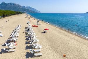 a beach with chairs and umbrellas and people on the beach at Camping Iscrixedda in Lotzorai
