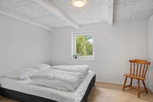 a bed in a room with a chair and a window at 80324-Ulfborg-Munkhulevej-6 in Staby +27 photos