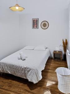 a white bedroom with a bed and a basket at Le Citadin - Centre - Wifi - Balcon in Dax