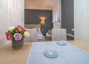 stół z dwoma talerzami i wazon z kwiatami w obiekcie Brera Luxury Suite w Mediolanie