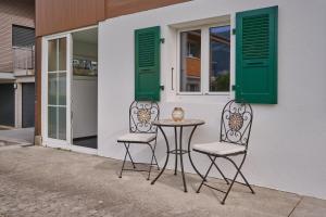 two chairs and a table in front of a building at Clarke's Lakeside Chalet 1 in Leissigen +2 photos