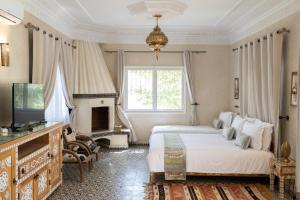 a bedroom with two beds and a tv and a fireplace at Villa du Cedre in Marrakesh