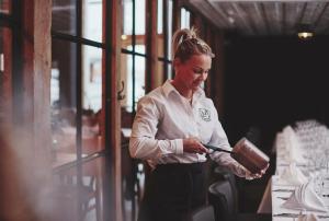 a woman standing in front of a table holding aecake at Havn Hotell og Restaurant in Skudeneshavn
