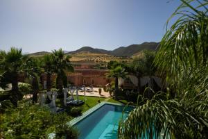 a view of a resort with a pool and palm trees at Villa du Cedre in Marrakesh