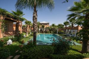 a swimming pool in a yard with palm trees at Villa du Cedre in Marrakesh