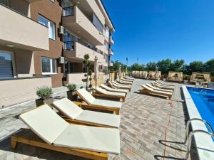 a row of lounge chairs next to a building with a pool at Apartment with pool in Veliko Gradište