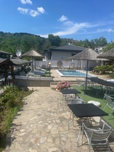 a patio with tables and chairs next to a pool at Семеен Хотел Сандим in Kŭrdzhali