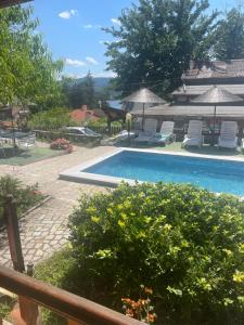 a swimming pool in a yard with chairs and umbrellas at Семеен Хотел Сандим in Kŭrdzhali