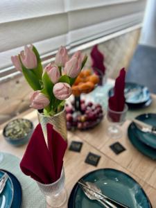 a table with pink tulips in a vase on a table at Irena Apartment near Aqua Park in Trebinje