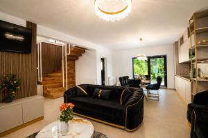 a living room with a black couch and a table at Cataleya House Sovata in Sovata