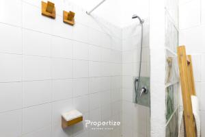 a shower in a white tiled bathroom at Il terrazzo sulla duna 6 by Propertize in Torre Dei Corsari