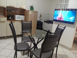 ein Glastisch mit Stühlen und ein Fernseher an der Wand in der Unterkunft Executivo central 101 in Ipatinga