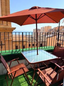 a table and chairs with an umbrella on a balcony at Eirenè Peaceful Suites in Agrigento