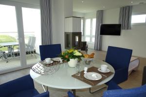 a living room with a white table and blue chairs at Sturmvogel in Olpenitz