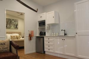 a kitchen with white cabinets and a living room at Greenlee Cottages in Canungra