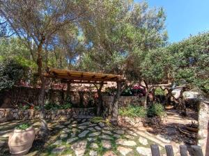 a garden with a stone wall and a wooden pergola at Residenza Conti Porto Istana in Porto Istana