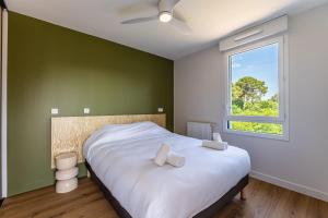 a bedroom with a bed with white sheets and a window at Apartment for 5 with a forest view in La Teste-de-Buch