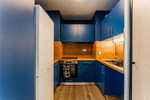 a blue kitchen with wooden cabinets and a white refrigerator at Apartment for 5 with a forest view in La Teste-de-Buch