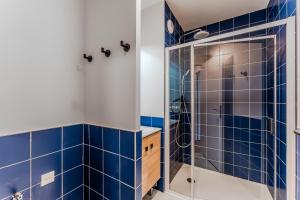 a bathroom with blue tiled walls and a shower at Apartment for 5 with a forest view in La Teste-de-Buch