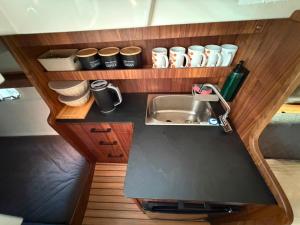 a small kitchen with a sink and cups on a shelf at Golden Yacht Solina in Polańczyk