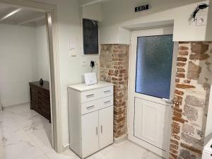 a kitchen with white cabinets and a brick wall at Chalikas Vintage Cottage in Mytilene +24 photos