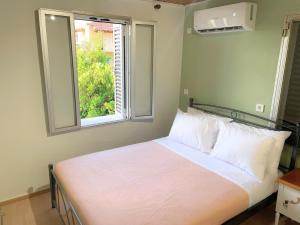 a bed with white pillows and a window in a room at Chalikas Vintage Cottage in Mytilene