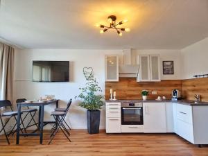 a kitchen with white cabinets and a table with chairs at FeWo Talblick - modern, charmant, Feldrand in Bad Orb