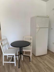 a black table and two white chairs and a refrigerator at Quarto privado na natureza in Fernao Ferro +6 photos
