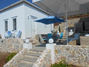 een patio met een blauwe parasol en een tafel en stoelen bij HydraVista (Pearl) in Hydra