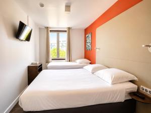 due letti in una stanza con pareti arancioni di Hotel Thonon Centre Le Comte Rouge a Thonon-les-Bains