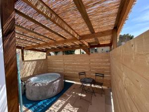 a patio with a hot tub and a table and chairs at Le cocon & spa in Camaret-sur-Aigues