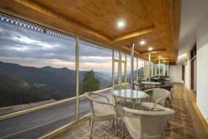 a balcony with tables and chairs and a view of the mountains at Narkanda Heights by Splendid Retreat Hotels in Nārkanda
