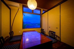 a room with a table and chairs and a window at Yufuin Ryokan Yufumomiji in Yufu