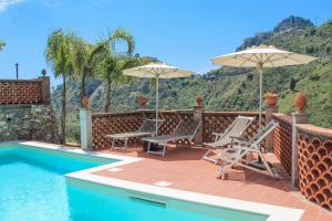 a patio with chairs and umbrellas next to a swimming pool at Casa Ziretto in Castelmola