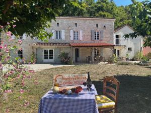 a table in front of a stone house with a bottle of wine at Combe Rouge in Belvèze