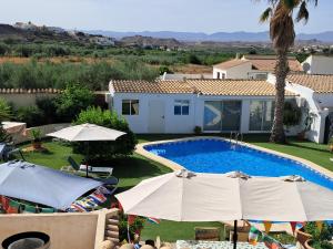a swimming pool with umbrellas and a house at Cortijo Esquina B&B Guesthouse in Arboleas