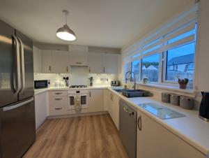 a kitchen with white cabinets and a stainless steel refrigerator at Spacious 5BR Home St Andrews in Fife