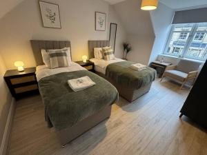 a bedroom with two beds and a chair and a window at Modern 3BR home in Cumbernauld in Cumbernauld