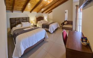 a bedroom with two beds and a table and a chair at Hostal Catequil in Cajamarca
