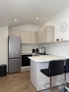 a kitchen with a refrigerator and a counter with two bar stools at Apartment Sidro in Posedarje
