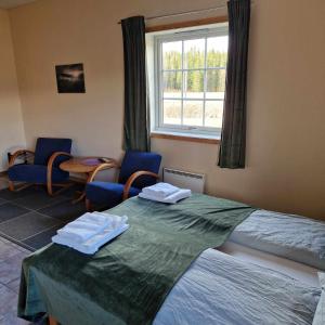 a room with two beds and chairs and a window at Svenningdal Camping in Svenningdal