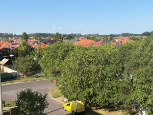 a yellow car parked under a large tree on a street at Kosbor apartman in Igricetanya