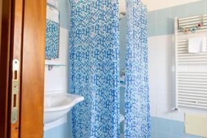 a bathroom with a blue shower curtain and a sink at Little Garden in Formia +7 photos