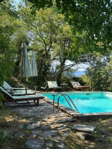 a swimming pool with two chairs and an umbrella at Authentic Stone House Tranquil Villa for Families and Groups in Grižane