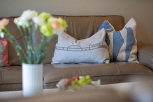 a couch with pillows and a vase of flowers on a table at Ferienhaus Marienleuchte in Marienleuchte +19 photos