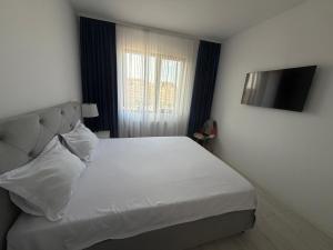 a bedroom with a white bed and a television at Royal Five Urban in Bucharest