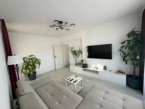 a white living room with a couch and a tv at Royal Five Urban in Bucharest